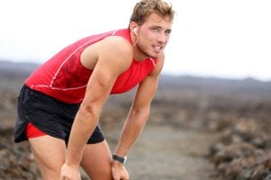 Man, resting from a run with his hands on his knees