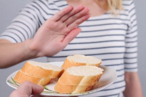 Woman putting her hand up, refusing a plate of white bread